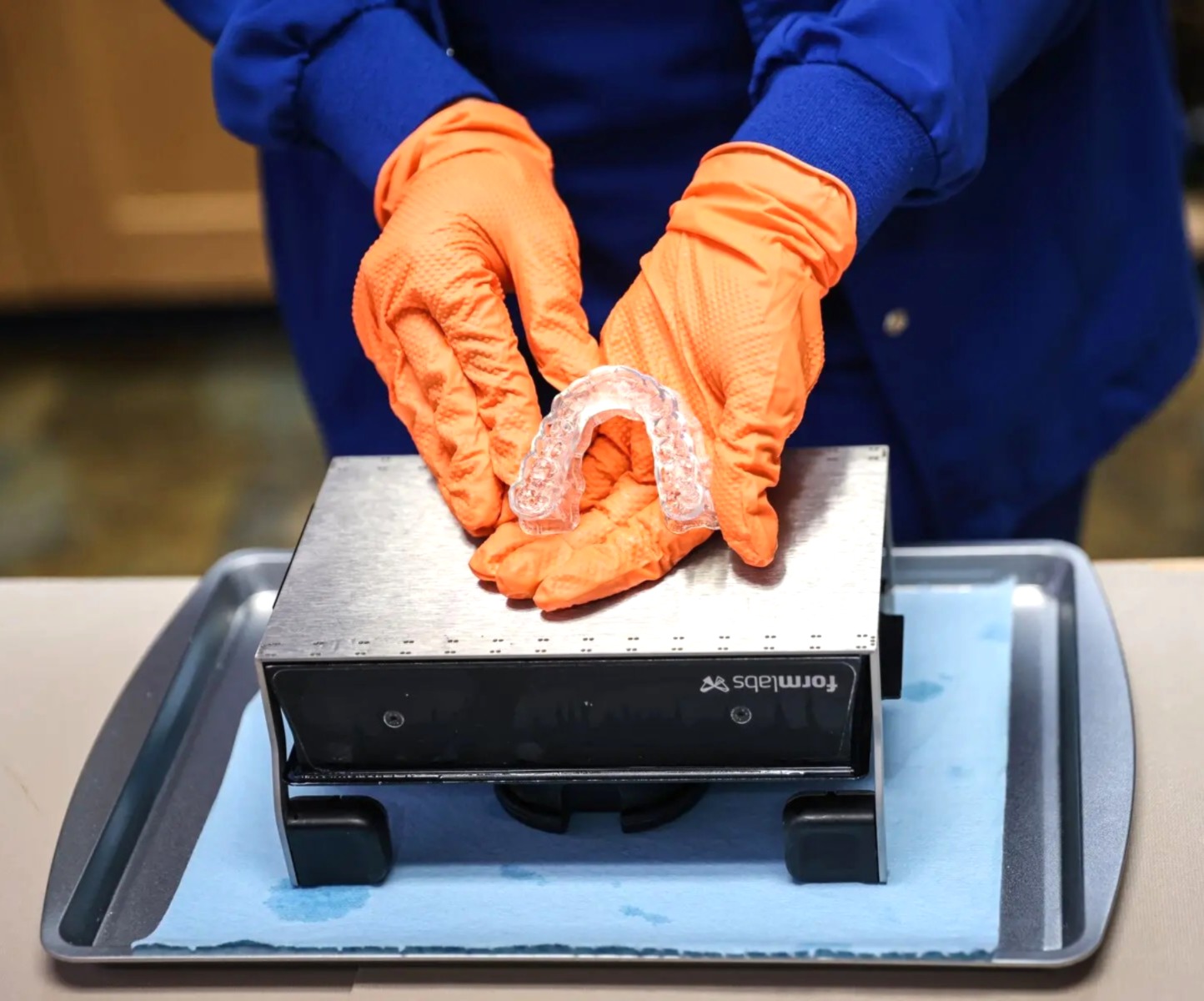 Técnico del laboratorio sosteniendo una férula de oclusión transparente recién terminada